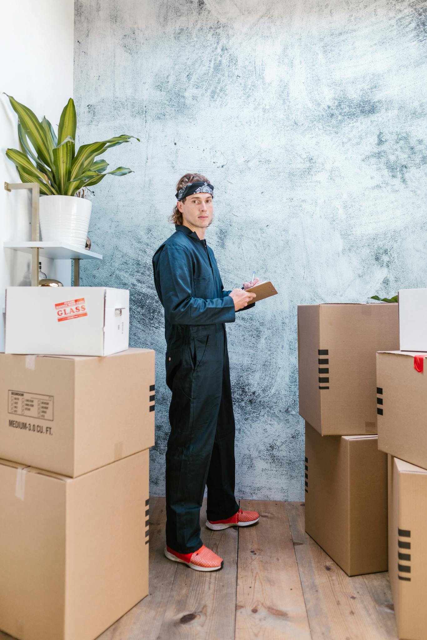 Man in Bandana and Coveralls Standing Near Packages